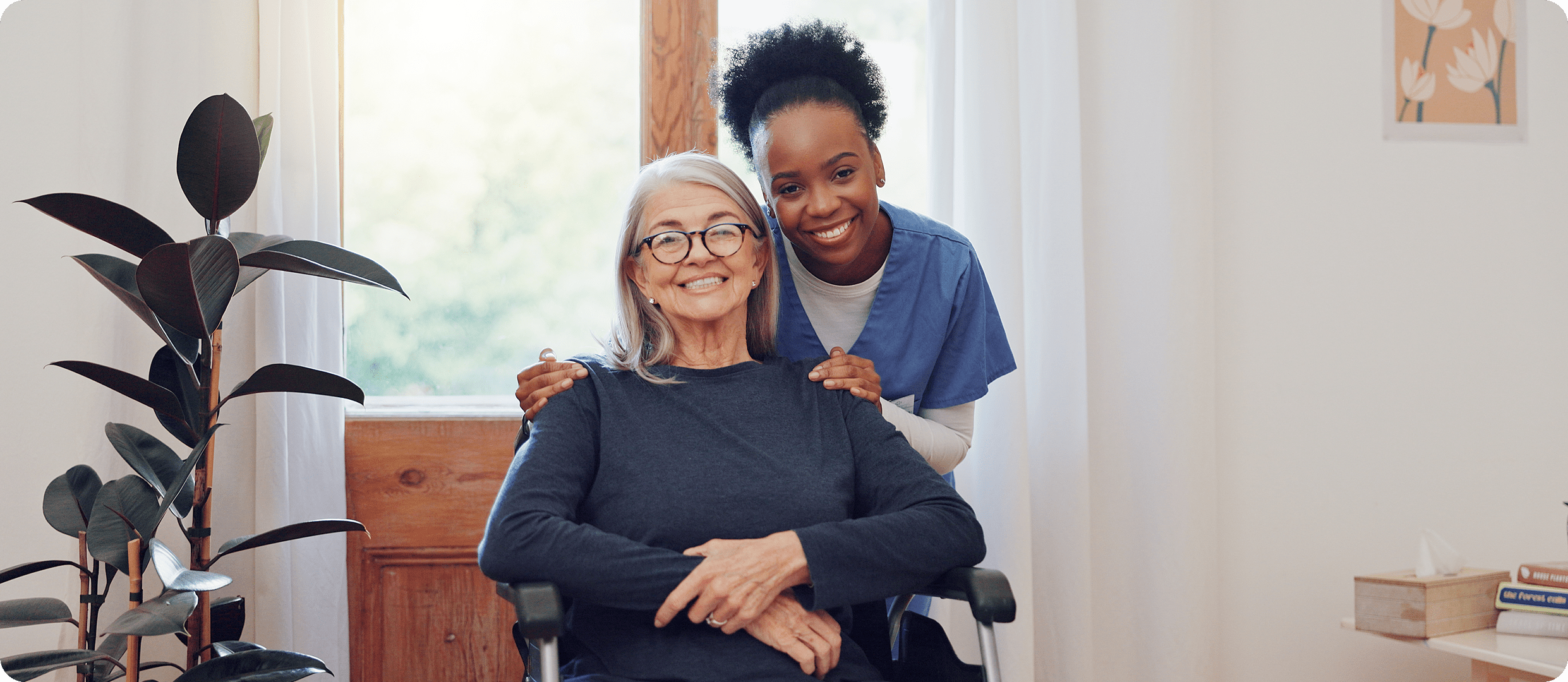 Caregiver smiling with elderly woman in wheelchair.