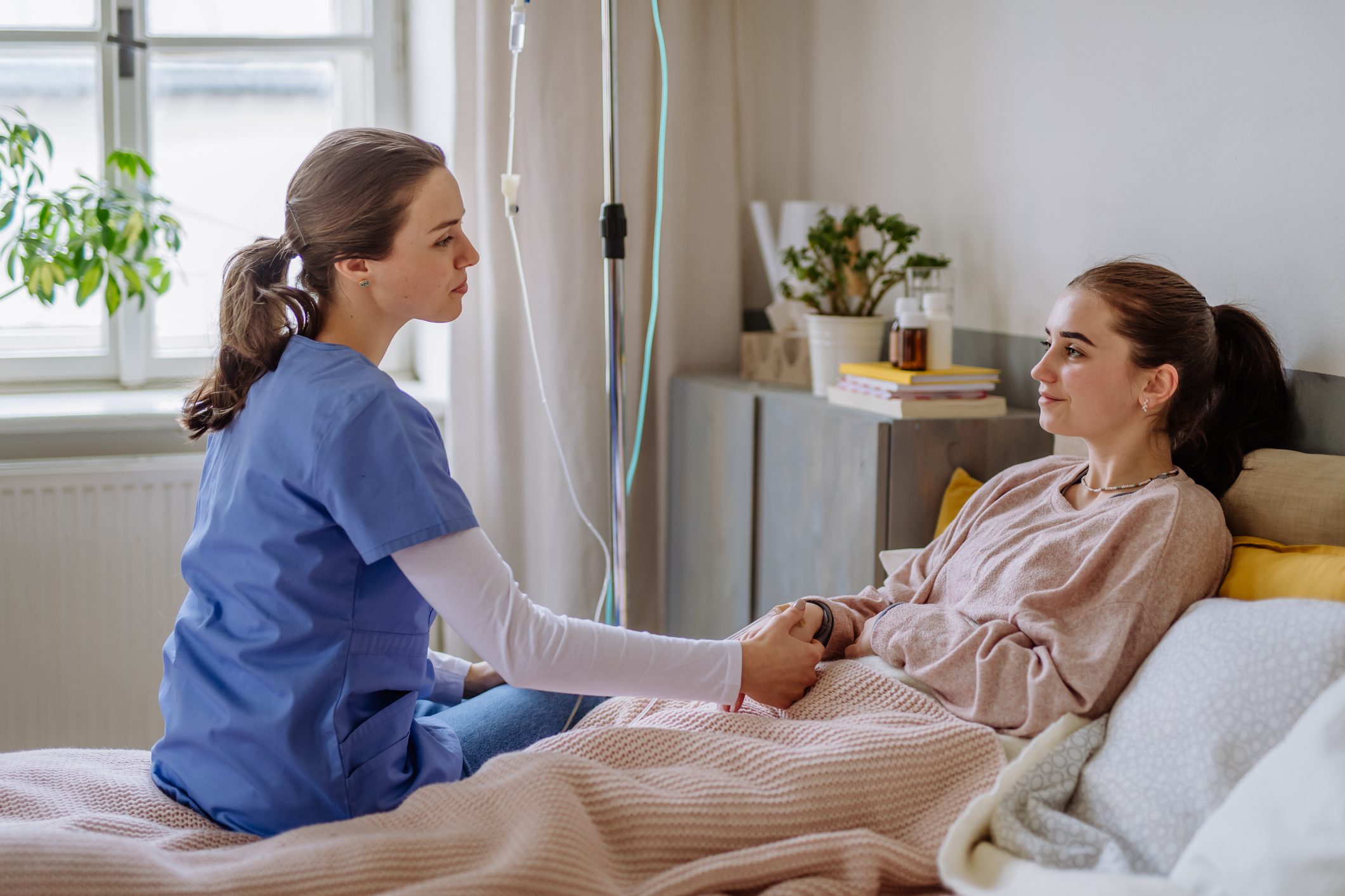Nurse comforting patient in hospital room.