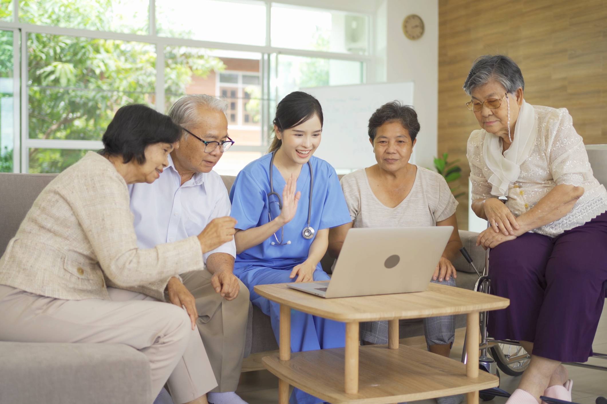 Elderly group and nurse watching laptop together.