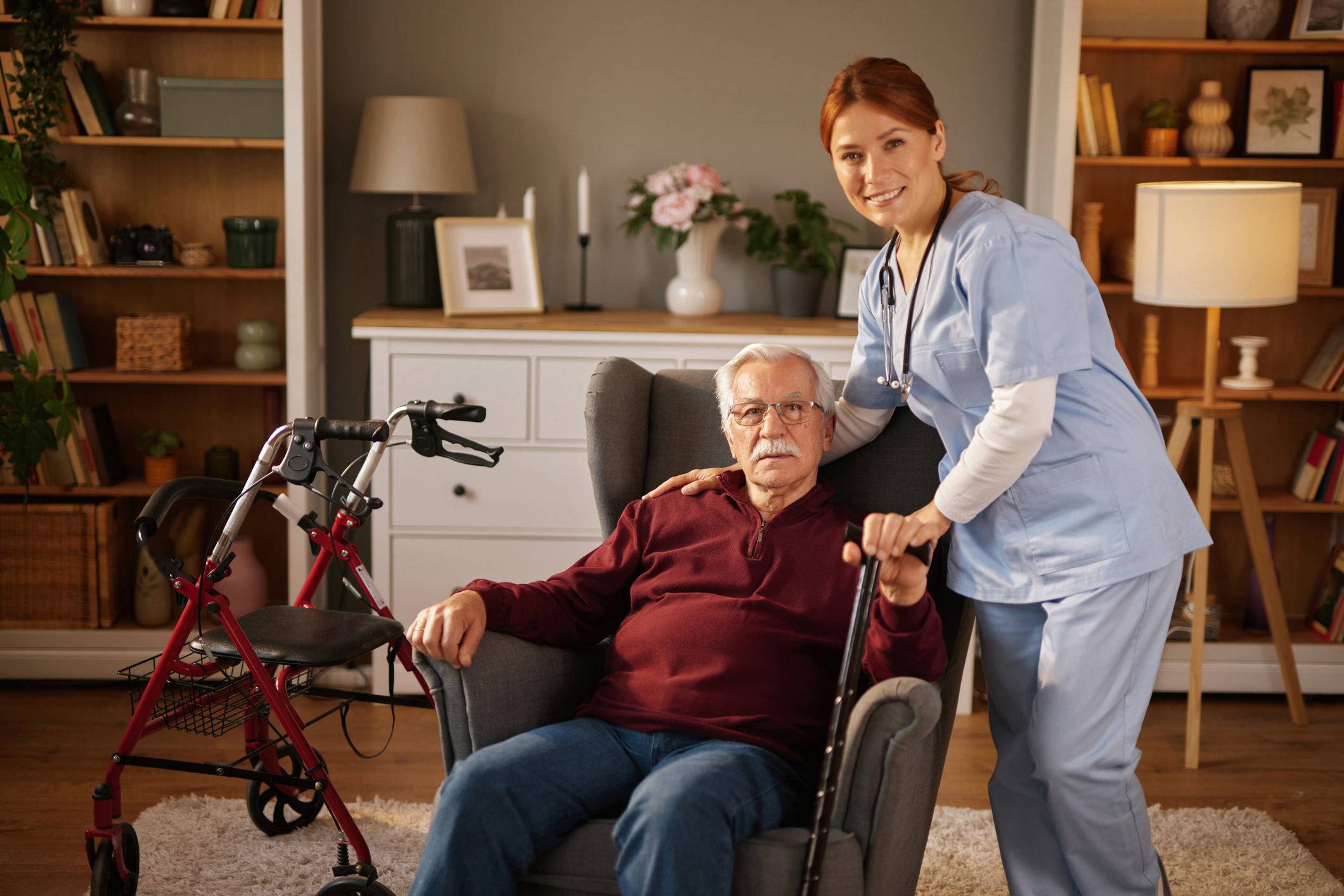Elderly man with caregiver in living room.