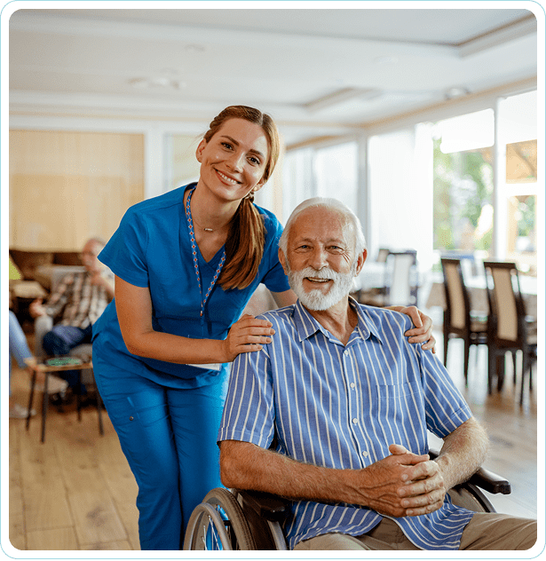 Nurse smiling with elderly man in wheelchair.